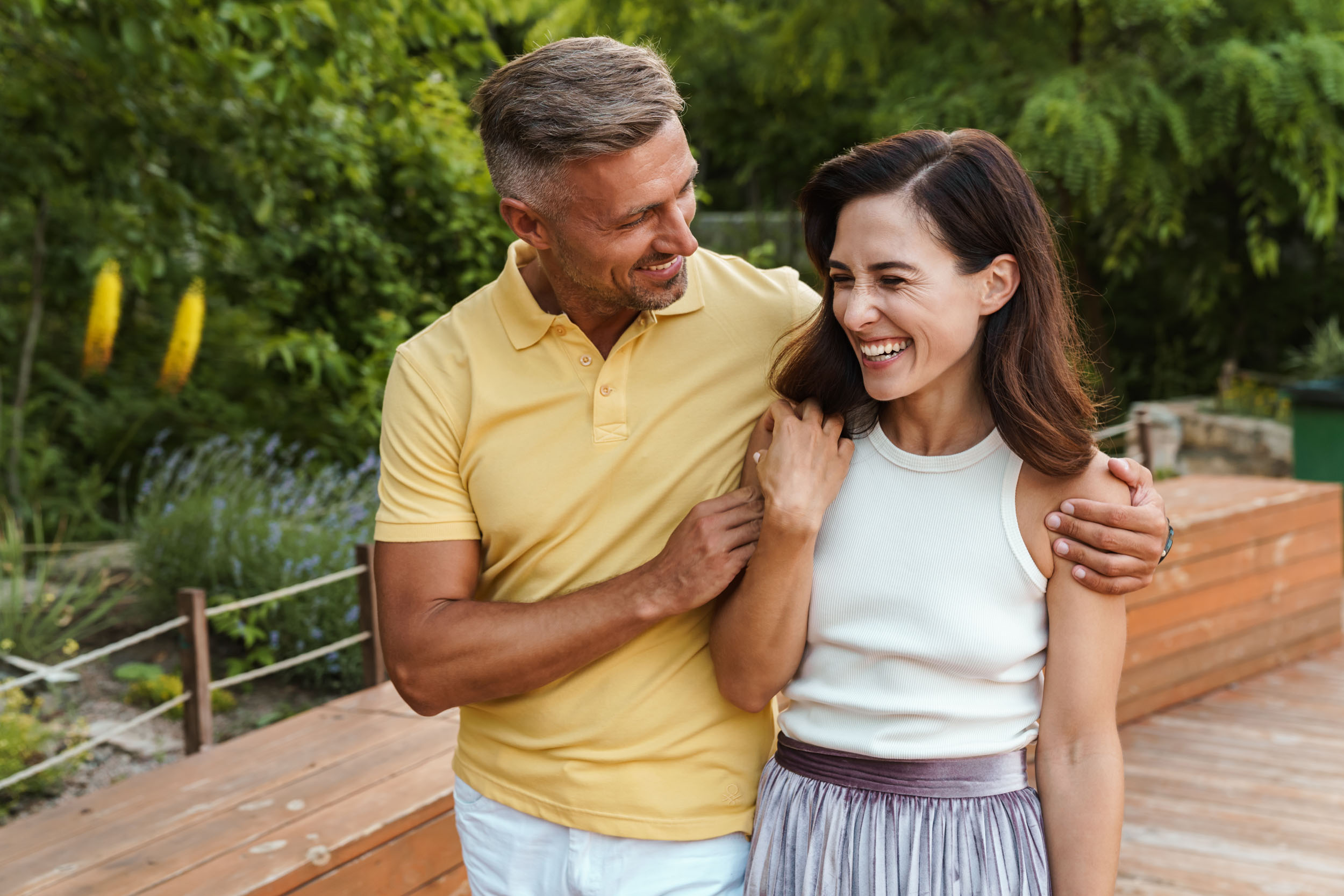 A man and woman stand together on a wooden deck enjoying the view around them