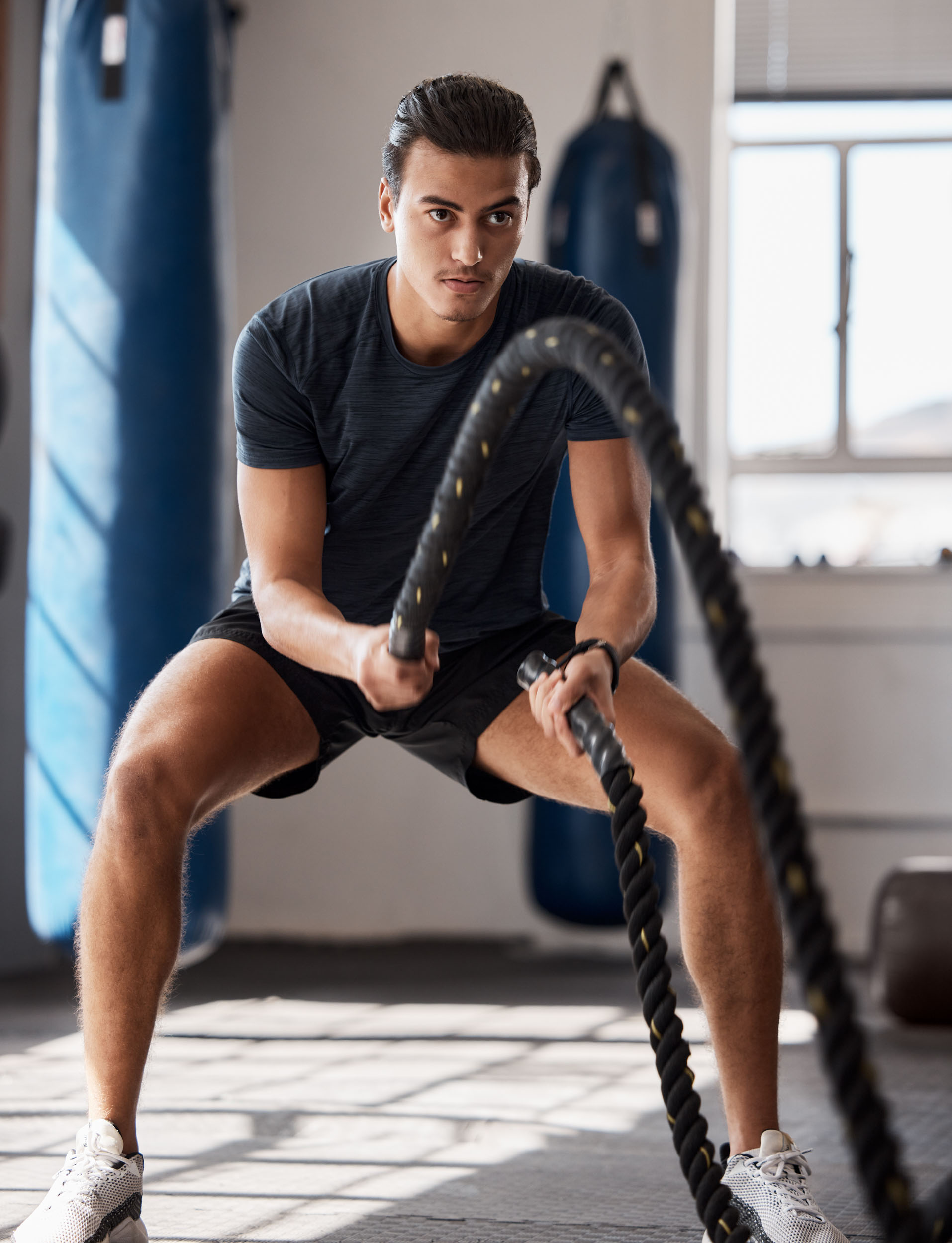 A man grips a battle rope preparing for a workout in a gym setting 1