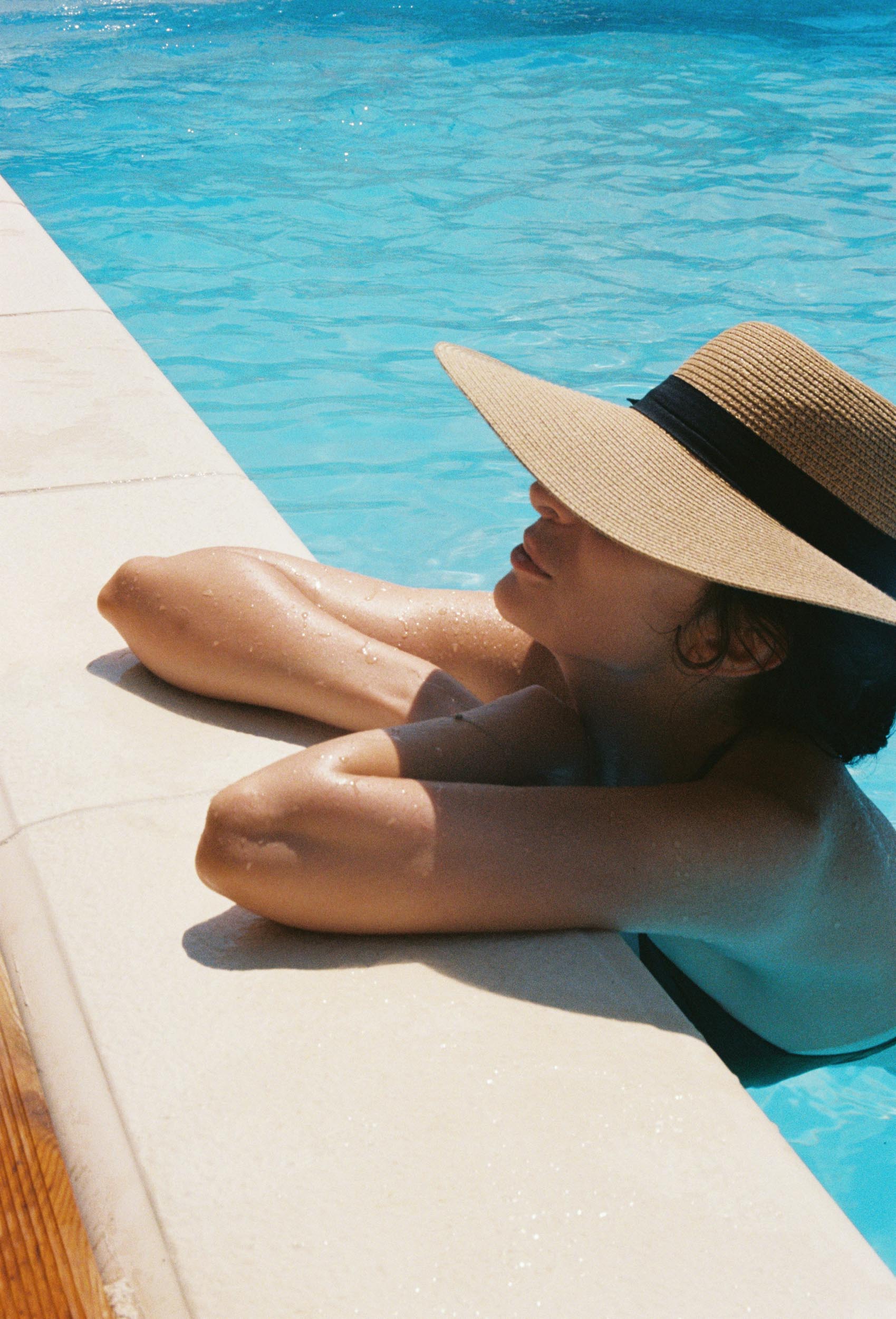 A woman in a hat relaxes in a pool enjoying the sun and water 1