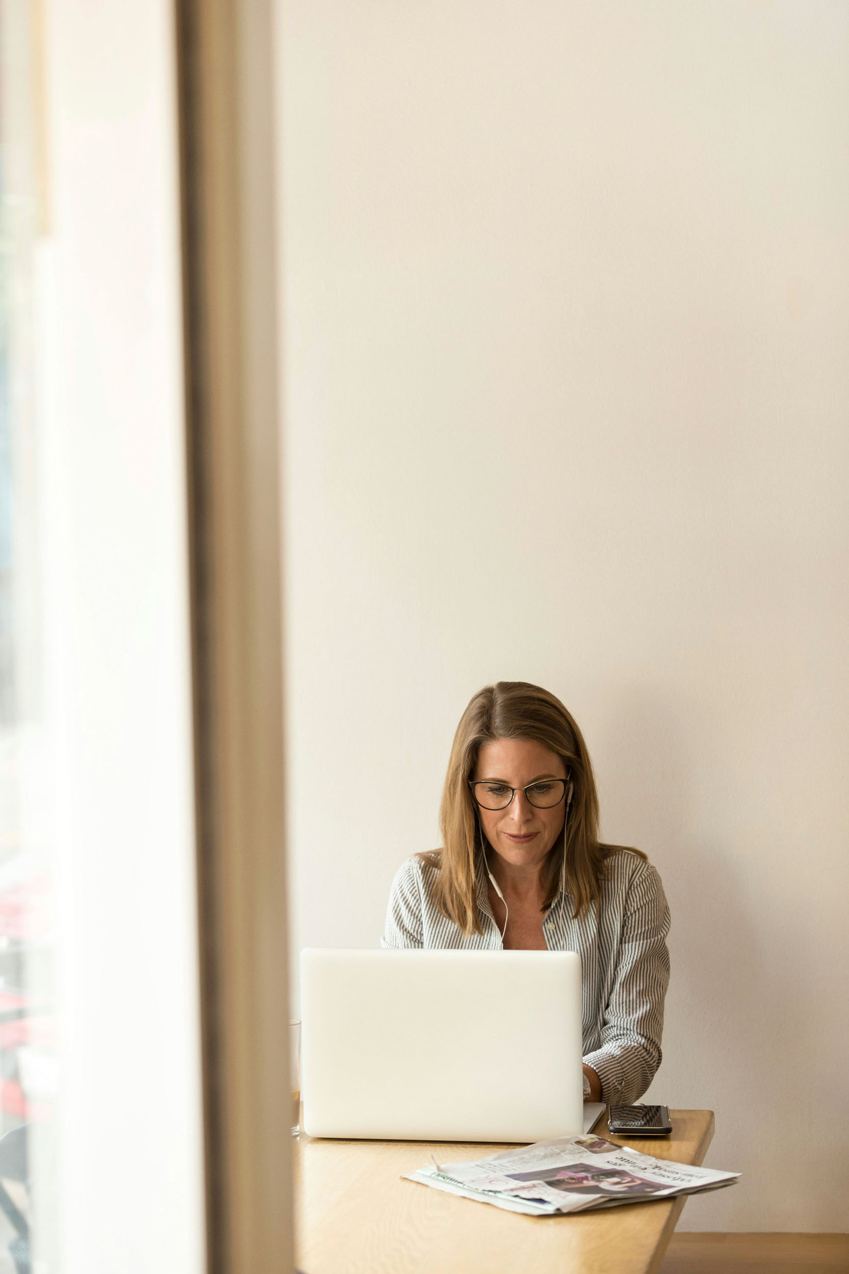 A woman sitting at a desk focused on her laptop with a cozy workspace around her 1