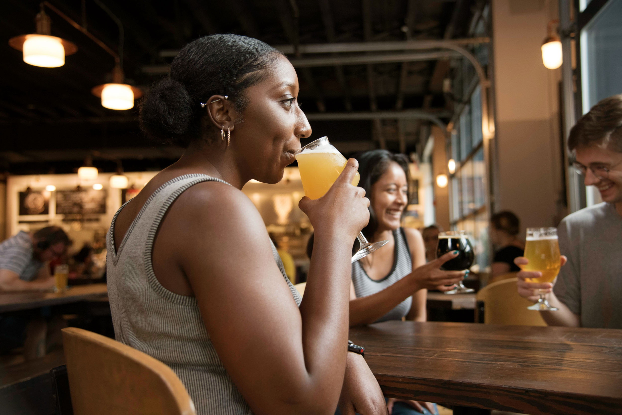 Three friends sitting at a table enjoying beers and chatting together 1