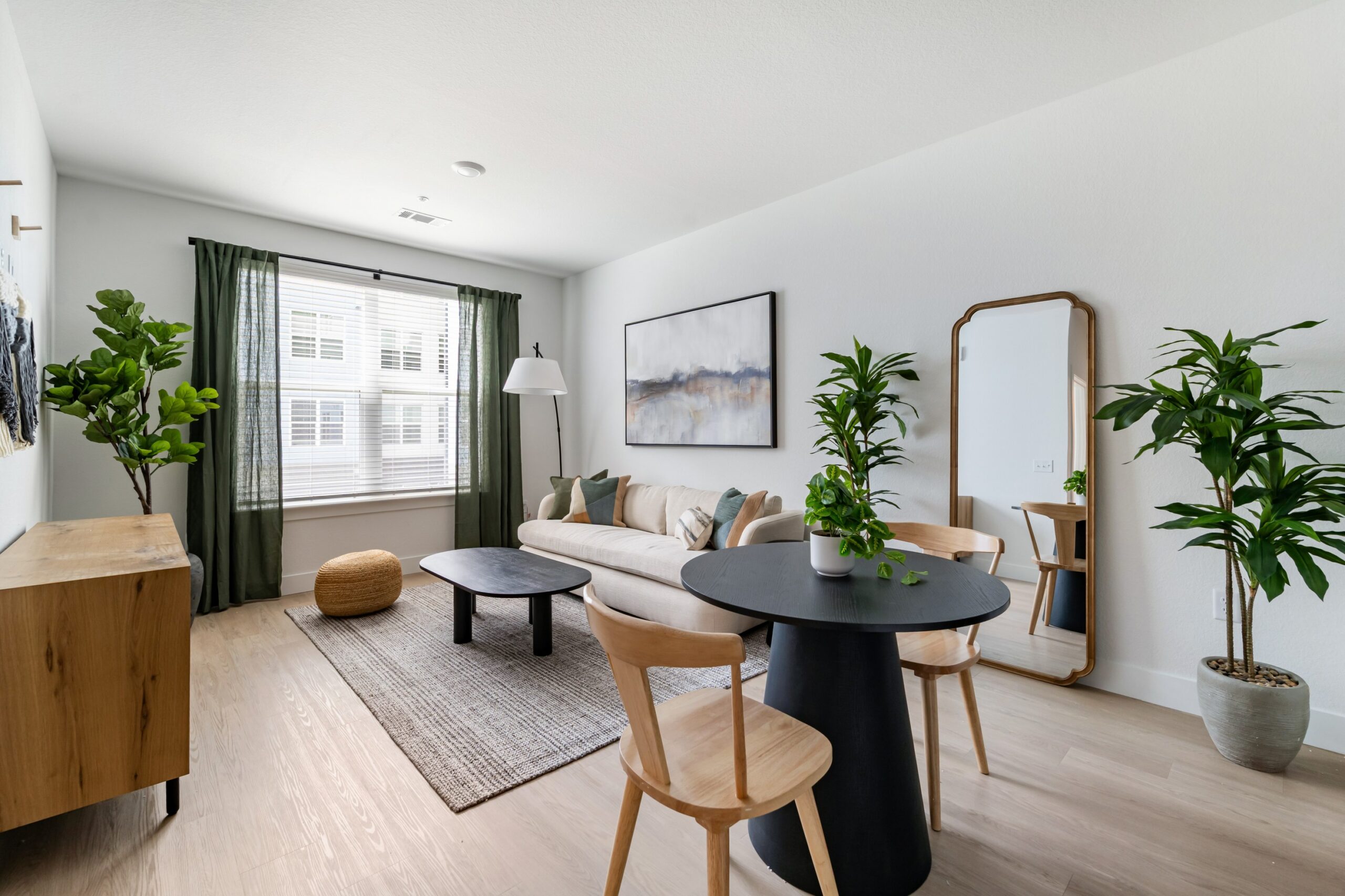 Model living room with hardwood-style flooring and ample natural light